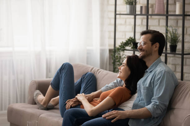 istock Happy dreamy young couple hugging, relaxing on cozy couch together 1308658939