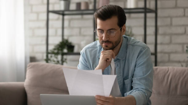 istock Close up serious man wearing glasses reading letter, checking documents 1308658945