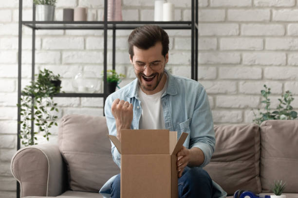 istock Overjoyed man wearing glasses looking into cardboard box, received parcel 1308658963