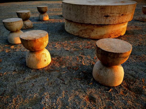 Târgu Jiu, Romania - November 9, 2020: Table of Silence monument by Romanian sculptor Constantin Brancusi. Artistic HDR side view at sunset of the hourglass shaped chairs surrounding the table, representing the passing of time. Sculptural ensemble situated in the city central park. Homage to the Romanian heroes of the First World War. UNESCO world heritage site. Beautiful travel destination for cultural tourism in Eastern Europe.
