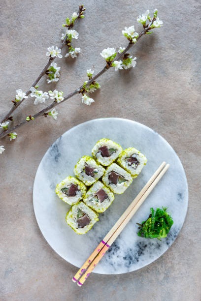 istock Japanese sushi served with spring cherry tree blossoming branches. Top view, close up on light background. 1308661947