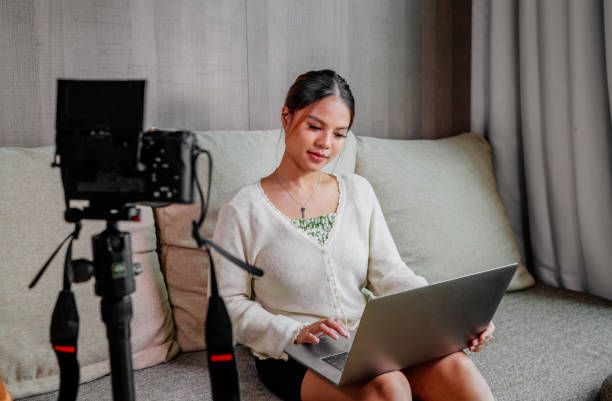 istock Asian blogger, podcaster or vlogger looking at camera and talking on video shooting with technology. Social media influencer people or content maker concept in relax casual style at home 1308663065
