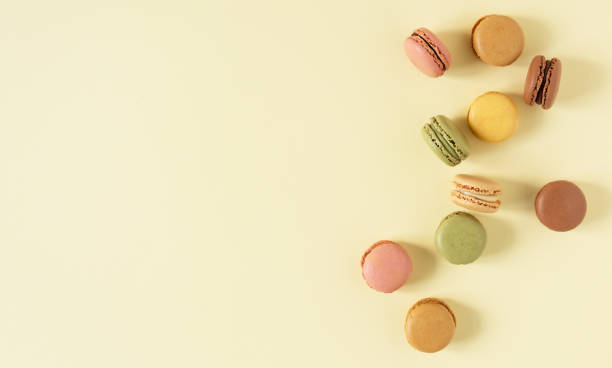 istock Multi colored french macaroons top view on yellow pastel background 1308665354