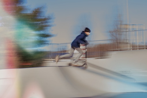 a teenage boy with his stunt scooter in a halfpipe in a skate park