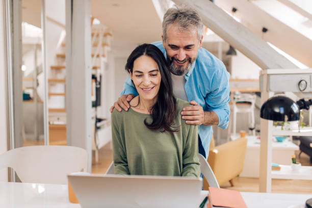 istock Mature woman working online and her husband helping her 1308670065