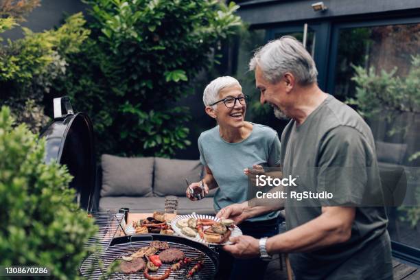 Senior Couple Grilling Meat And Enjoying In The Backyard Stock Photo - Download Image Now