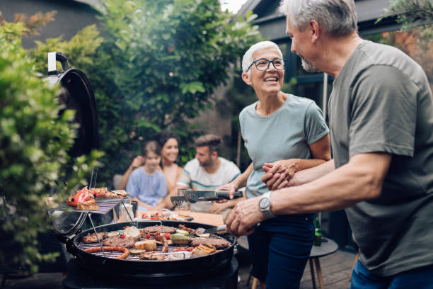 Happy senior couple enjoying making barbecue for their family Senior couple preparing barbecue for the whole family at the backyard. bbq stock pictures, royalty-free photos & images