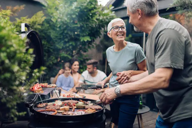 Photo of Happy senior couple enjoying making barbecue for their family
