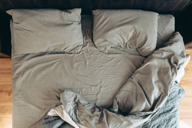 top view of messy bed with gray sheets