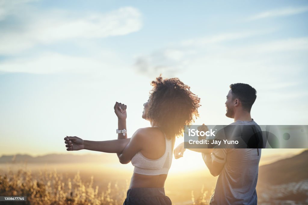 We like to get it on first thing in the morning Shot of a young couple stretching while out for a workout on a mountain road Healthy Lifestyle Stock Photo