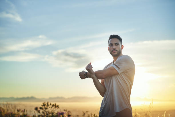 Shot of a young man stretching while out for a workout on a mountain road