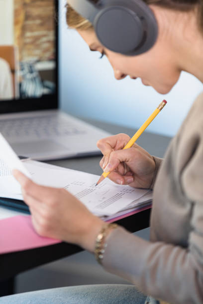istock Close up female student with headphones working on schoolwork 1308679954