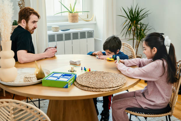 istock Father and kids playing with board game together at the table 1308681368
