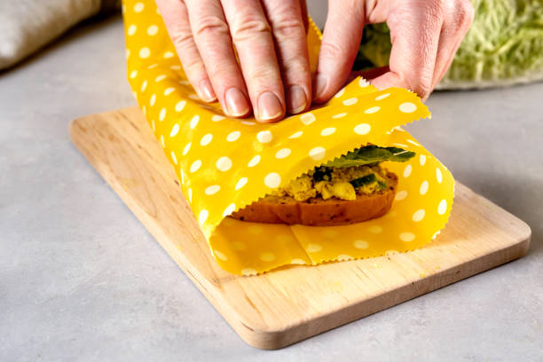 Woman hands wrapping a healthy sandwich in beeswax food wrap and cotton bag Zero waste and plastic free concept. Woman hands wrapping a healthy vegan sandwich in beeswax food wrap for lunch. Eco-friendly, reusable wax cloth and cotton bags beeswax photos stock pictures, royalty-free photos & images