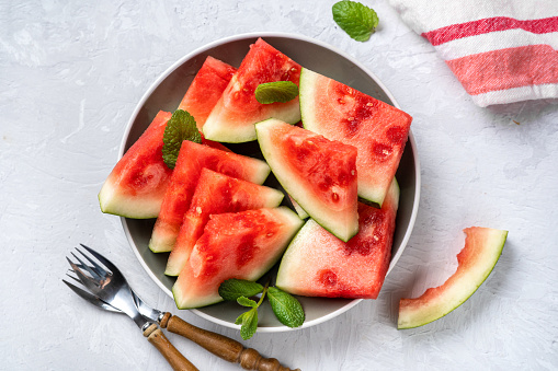 Sweet, juicy and ripe watermelon pieces in a plate on light background. Top view. Summer food concept. Enriched raw vegan food