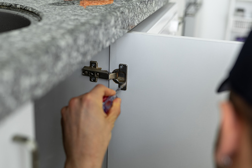 Repairman install cabinet hinge
