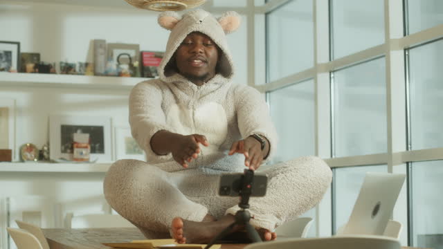 Missing a friend during lockdown. African man doing video call in cute bear onesie. Using smart phone