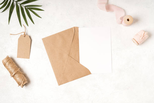 istock Blank white card with craft paper envelope in hands 1308684710