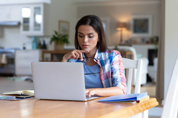 istock Caucasian woman sitting by desk working from home using laptop 1308685312