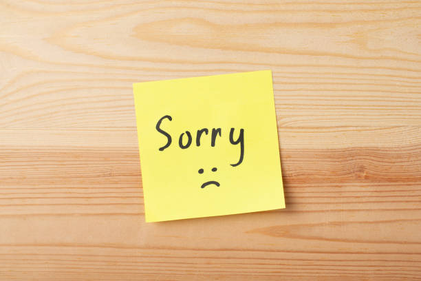 Yellow sticky note with inscrition SORRY on wooden table