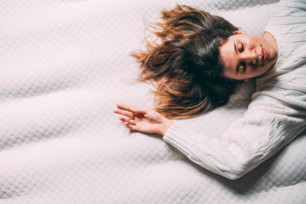 Young woman lying in bed stock photo