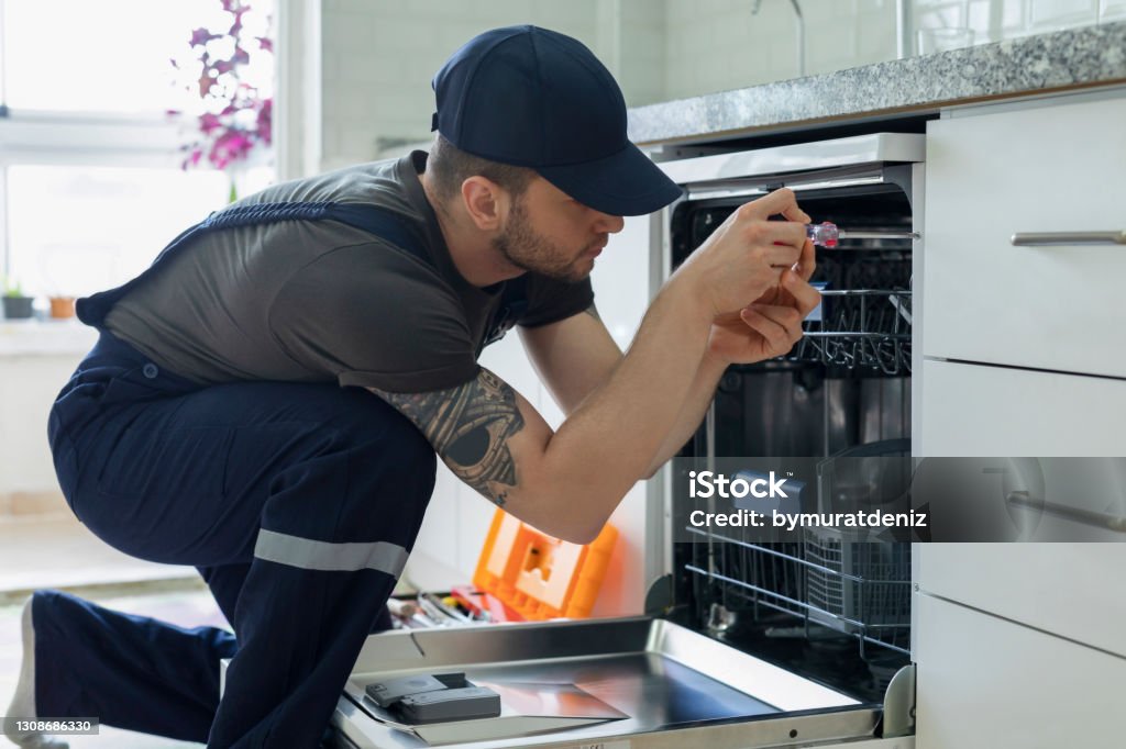 Technician examining dishwasher Appliance Stock Photo
