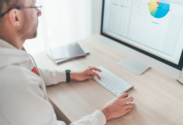 istock Finance asset manager man in eyeglasses using modern computer with a wireless keyboard and mouse evaluating money growth. Home office, investing or freelance work on worldwide quarantine time concept 1308686647