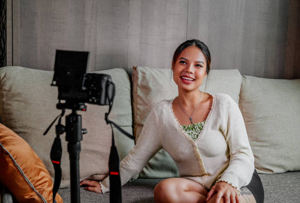 istock Asian blogger, podcaster or vlogger looking at camera and talking on video shooting with technology. Social media influencer people or content maker concept in relax casual style at home 1308689536