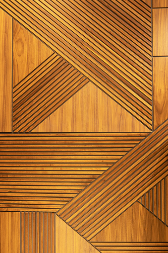 Designer walnut veneer panel, geometric crisscross pattern wood wall. Architectural background, texture. The concept is a modern interior, natural materials, minimalism style. Vertical.