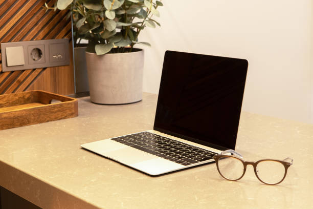 istock Workplace in apartment or cafe with modern interior. Open laptop and glasses on the table top. Business concept, remote work from home, distance learning, use of technology. Place for text, layout 1308690470