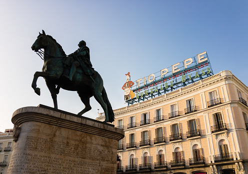Puerta del Sol in Madrid, January 23, 2020. Classic and loved by the locals, the sign of the Gonzalez Byass company in its new location, and its Jerez Tio Pepe wines. Equestrian statue of Carlos III.