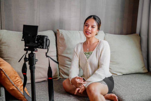 istock Asian blogger, podcaster or vlogger looking at camera and talking on video shooting with technology. Social media influencer people or content maker concept in relax casual style at home 1308694145
