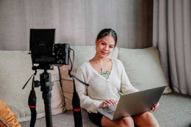 istock Asian blogger, podcaster or vlogger looking at camera and talking on video shooting with technology. Social media influencer people or content maker concept in relax casual style at home 1308698615