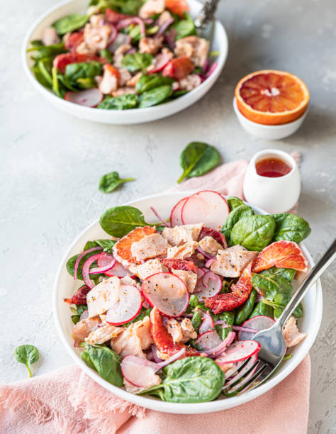 istock Fresh salad with salmon, spinach, radish and red oranges served with orange sauce, light concrete background. 1308699545