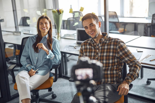 istock Two cheerful coworkers streaming a live video from the office 1308700221