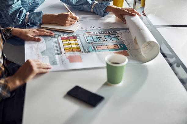 istock Male engineer and his experienced coworker modifying the house plan 1308700252
