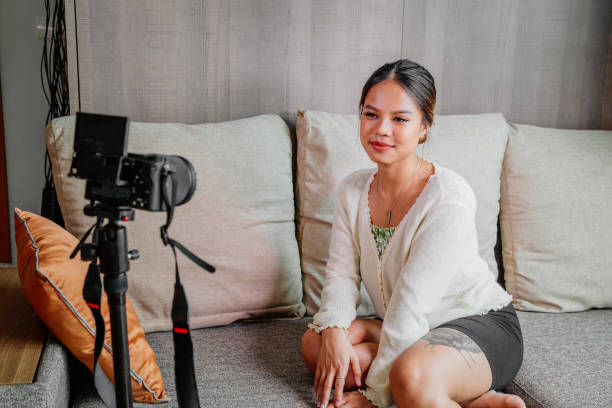 istock Asian blogger, podcaster or vlogger looking at camera and talking on video shooting with technology. Social media influencer people or content maker concept in relax casual style at home 1308702780