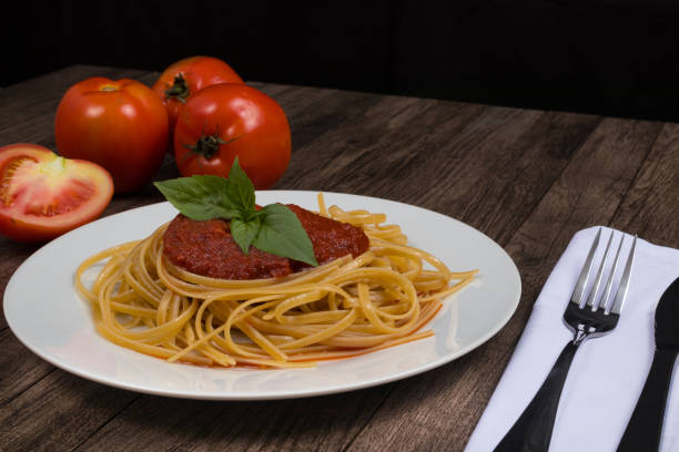 istock Pasta with red sauce and basil leaves. Tomatoes in the background. Space for text 1308703788