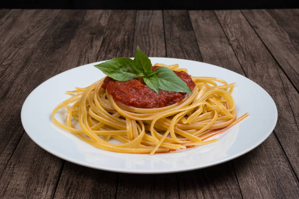 Pasta with sugo sauce and basil leaves served on a white plate. Photography with centralized elements. Italian gastronomy