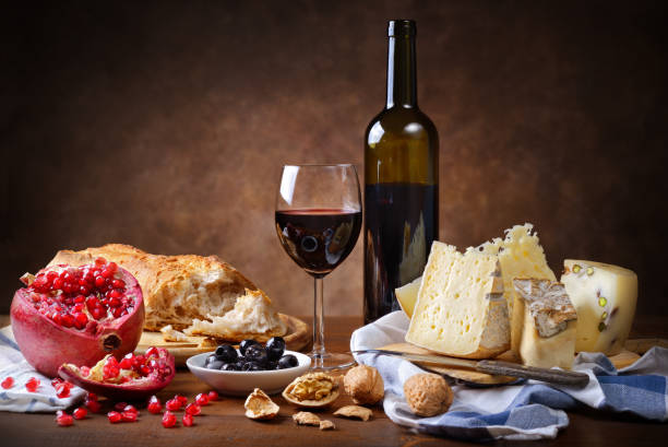 Red wine, cheese, walnuts, olives, pomegranate and bread. Rustic meal, copy space. merlot grape photos stock pictures, royalty-free photos & images