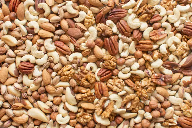 Photo of Assorted nuts: hazelnuts, walnuts, brazilian nuts, pecans, pistachio, almonds, cashews Flatlay organic mixed nuts background. Healthy food, useful microelements and vitamins. Useful health snack.