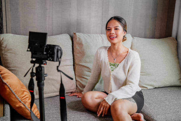 istock Asian blogger, podcaster or vlogger looking at camera and talking on video shooting with technology. Social media influencer people or content maker concept in relax casual style at home 1308704857