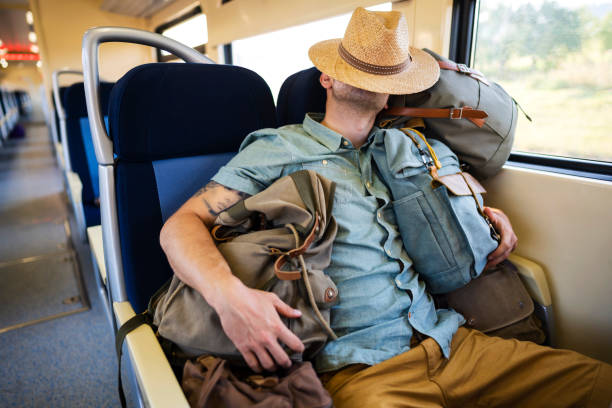 istock Young man sleeping on a train with a hat on his head 1308705526