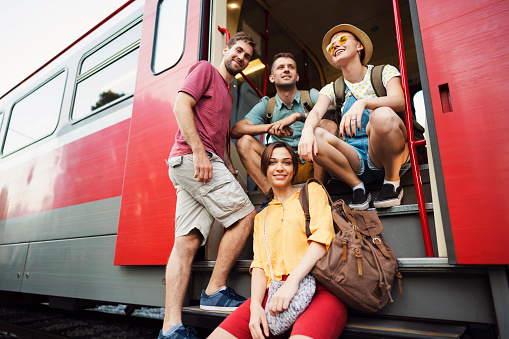 Low angle view of a small group of young Caucasian people at the train door posing for the photo.