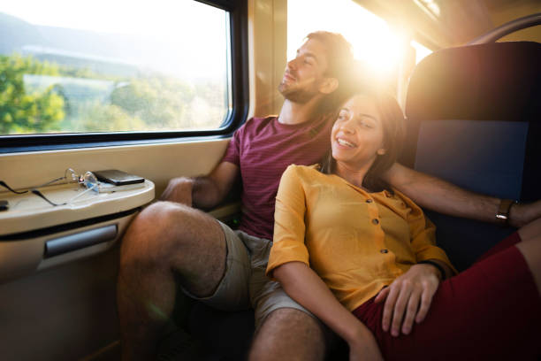 Young couple riding on the train, relaxing while looking through the window together