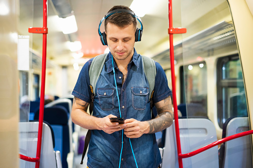 Young Caucasian man with headphones on the train.