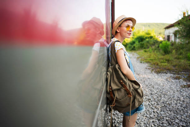 Side view of a young caucasian woman leaning on the train and waiting to board on.