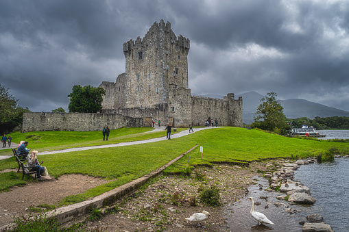 Killarney, Ireland, August 2019 People sightseeing and visiting beautiful, 15th century Ross Castle near Lough Leane with stormy clouds, Ring of Kerry