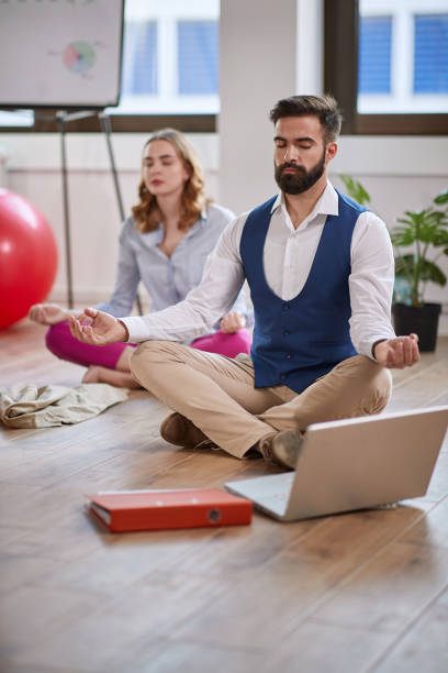 istock man meditating at work.coworkers meditating together at work. 1308711703