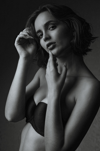 Fashion portrait of wonderful brunette model wears black lingerie posing in the dark studio. Monochrome color
